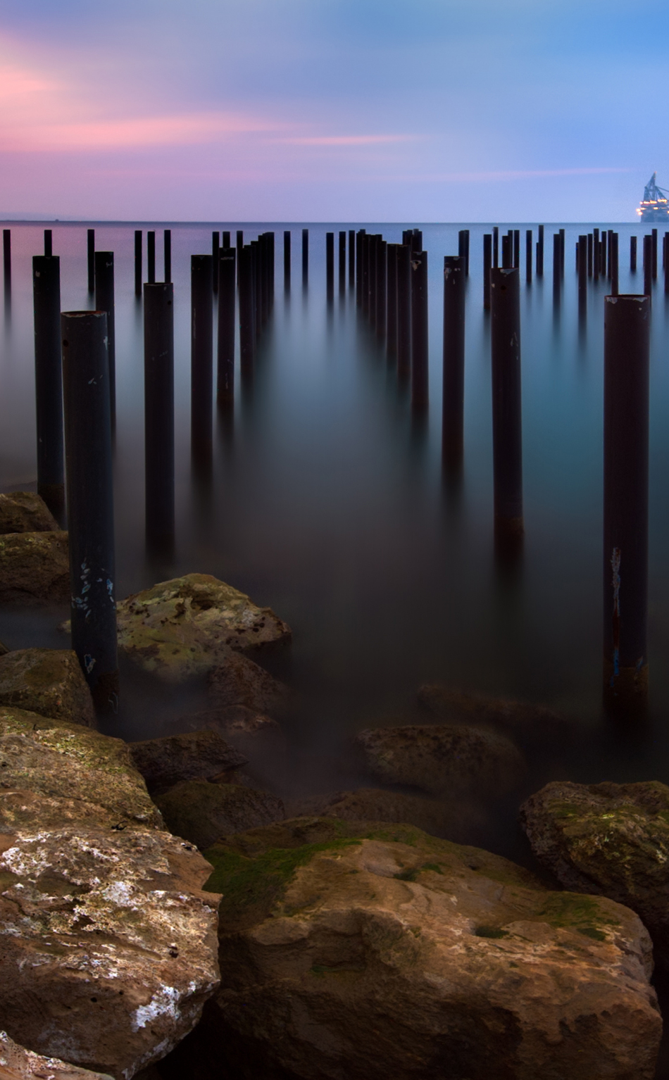 Download wallpaper 950x1534 seascape, sunset, wooden poles, iphone