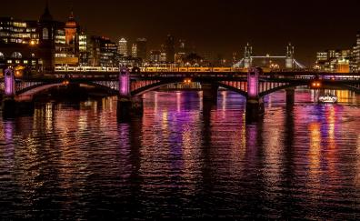 City, night at bridge, colorful glow on water