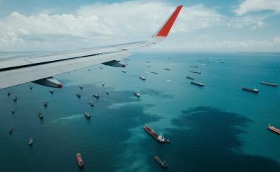 Airplane wing, boat, sea, aerial view